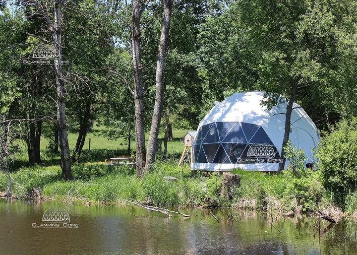 white geodesic dome tent on round platform by the pond