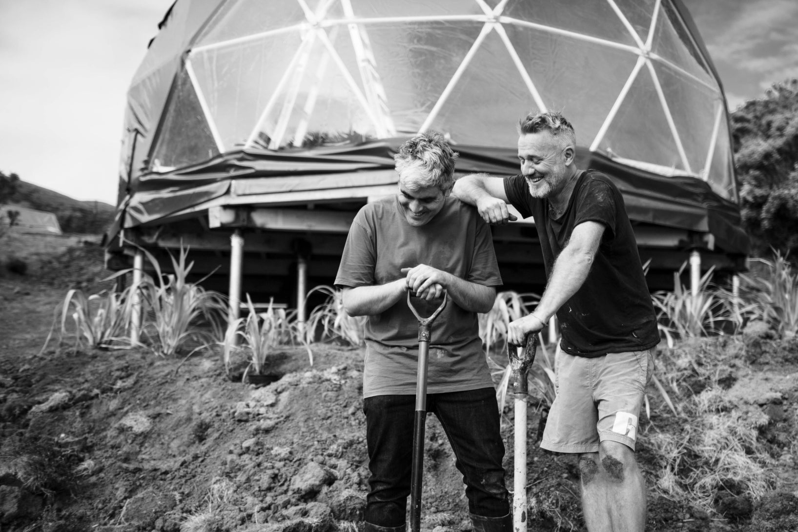 Two men standing in front of a geodesic dome structure in a natural setting close to Wellington, NZ. Dome was supplied by Glamping Dome Store
