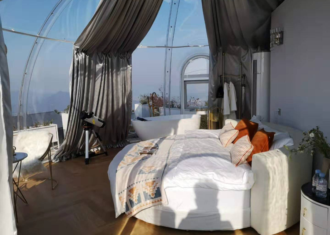 Bedroom with a large bed, curtains, and a view of the outdoors inside poilcarbonate dome