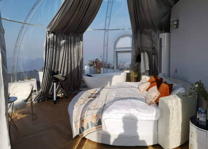 Bedroom with a large bed, curtains, and a view of the outdoors inside poilcarbonate dome