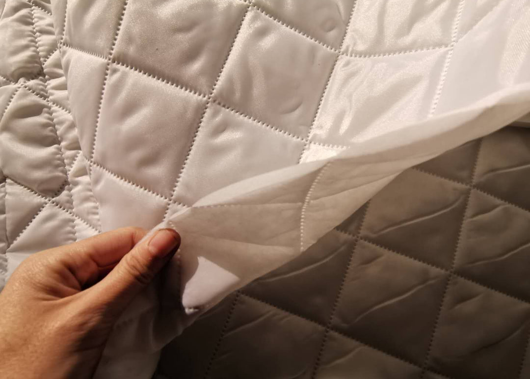 Close-up of a quilted fabric insulation for dome tent with a hand touching it