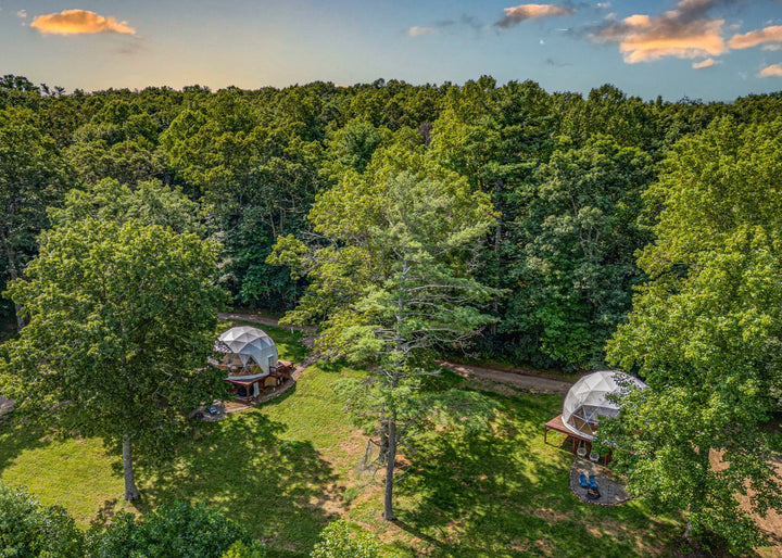 Two geodesic domes nestled among trees in a forest setting