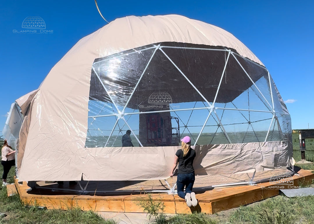 Geodesic dome structure with a transparent panoramic window panel, people around, and clear blue sky.