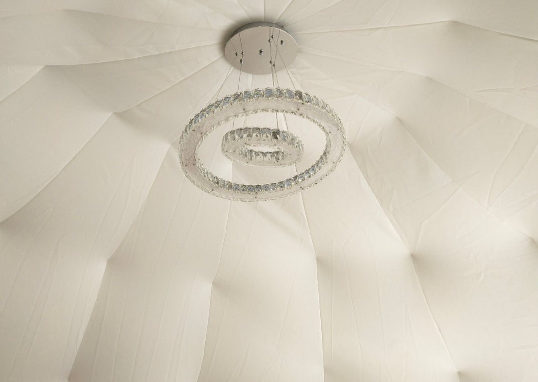 Elegant beige stretchy dome decor space liner (1/8'' or 3 mm thick) installed inside a Glamping Dome Store geodesic dome tent, featuring a modern hanging light fixture—ideal for glamping setups or those looking to buy a geodesic dome tent.